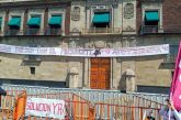 Manifestantes exigen diálogo con AMLO por caso Ayotzinapa; colocan manta debajo del Balcón Presidencial